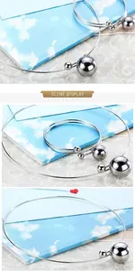 Vue détaillée de sphères argentées polies sur un collier et bracelet minimalistes rigides