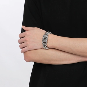 Detail of a chunky silver stainless steel Cuban chain bracelet with a skull clasp on wrist