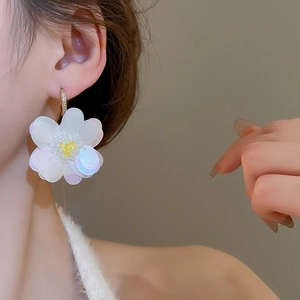 Elegant white sequin flower earring with zircon inlay worn by model on warm background