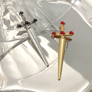 Close-up of gothic sword earrings in silver and gold metal with inset gemstones