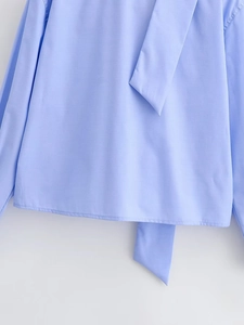 Close-up of light blue woven shirt fabric with detail of cuff and hem stitching