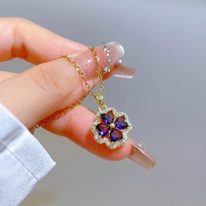 Macro detail of gold four-leaf clover pendant with purple heart stones and crystal halo