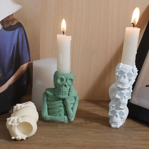 Macro detail of skeleton candlestick mold with green thinker skull and plaster pillar