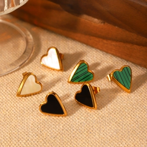 Golden heart earrings with white, black, and green inlay displayed on beige linen