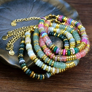 Close-up of colorful natural stone bead bracelets with gold hardware in a ceramic bowl