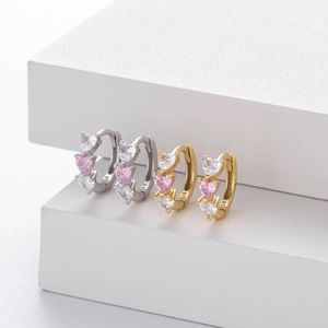 Macro shot of S925 sterling silver heart-shaped huggie earrings with pink and white cubic zirconia