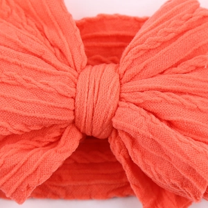 Close-up of orange cable knit baby headband featuring a large textured bow detail