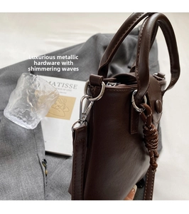 Detail of vintage brown leather handbag with silver metal ring and woven rope charm