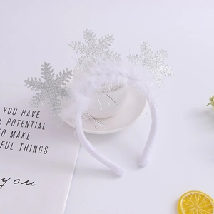 Close-up of a white plush headband with silver glittery snowflakes and soft feathers