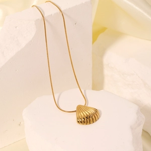 Elegant gold shell pendant necklace with snake chain on white plaster and silk fabric