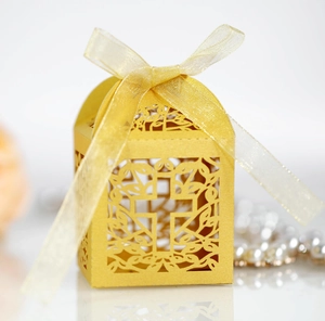 Detail of laser-cut golden cross pattern on favor box with elegant satin ribbon