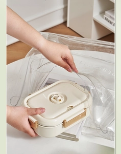Detail of insulated lunch box with sealing ring being placed in a clear carrying bag