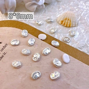 Close-up of silver irregular baroque pearl nail charms sized 8x6mm with vintage props