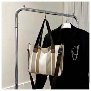 Detail of canvas tote bag showing vertical stripes and adjustable brown shoulder strap