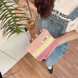 Close-up of a striped knit makeup bag with pink yellow red and white color blocking