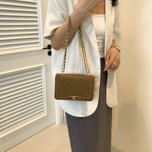Detail of olive brown quilted crossbody bag with gold chain strap and metallic lock
