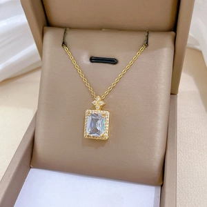 Macro shot of gold-plated necklace with emerald-cut zirconia pendant in brown velvet box