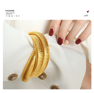 Detail of gold-plated triple snake wrap bracelet on white blazer sleeve for elegant styling