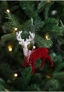 Red flocked reindeer ornament with silver glitter on a festive Christmas tree branch