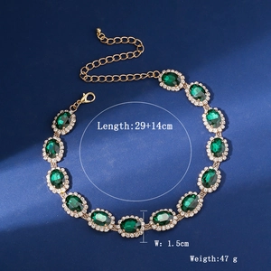Macro detail of multi-layer crystal necklace with green oval gemstones and gold base