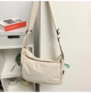 Close-up of beige nylon messenger bag showing wide shoulder strap and zip pocket
