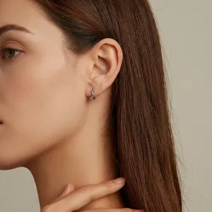 S925 sterling silver snake earrings with textured pattern and green zircon on model ear