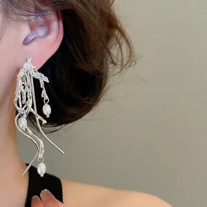 Modern irregular silver tassel earrings with white pearls shown on a model's ear