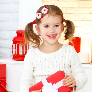 Close-up of a child wearing Santa Claus hair clips with festive Christmas background