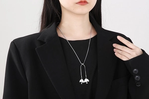 Détail d'un collier chaîne serpent argenté avec deux pendentifs arbre de vie sur modèle