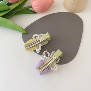Floral fabric hair clips with pearls in yellow and purple set on a minimalist background