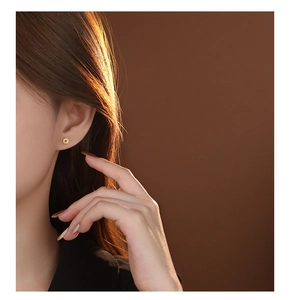 Macro detail of model wearing gold coin stud earrings made of S999 sterling silver