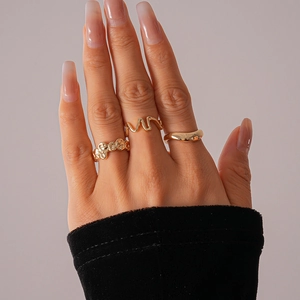 Detailed close-up of a three-piece gold irregular pleated geometric ring set on fingers