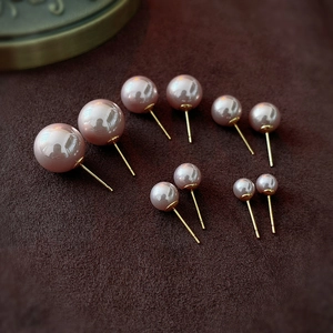 Close-up of five pairs of mauve pearl stud earrings in various sizes on velvet