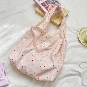 Detail of pink floral tote bag with brand label on soft white textured background