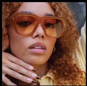 Close-up of vintage butterfly sunglasses with amber frames and metal rivets on model