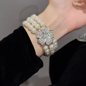 Detailed close-up of a triple-strand pearl bracelet with a sparkling floral rhinestone clasp