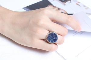 Fashionable large round ring with blue druzy crystal texture worn on a hand