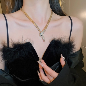 Chunky gold snake chain necklace with rhinestone pendant worn by model on black background