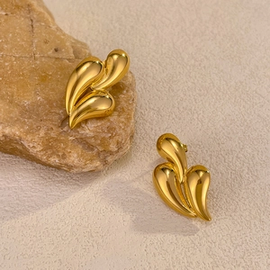 Detailed macro shot of golden teardrop earrings on a natural stone with polished finish