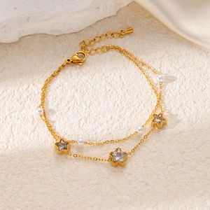 Detail of gold double-layer chain bracelet with star charms and elegant white pearls