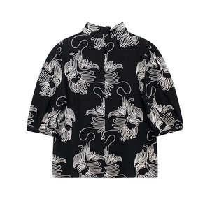 Close-up of intricate white embroidery on a black half-turtleneck loose blouse