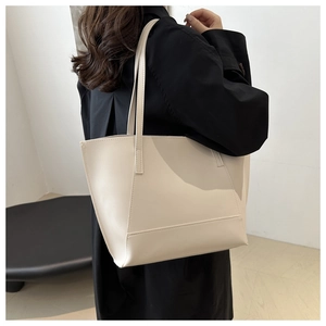Detailed side view of minimalist beige leather tote bag worn by a model for daily commute