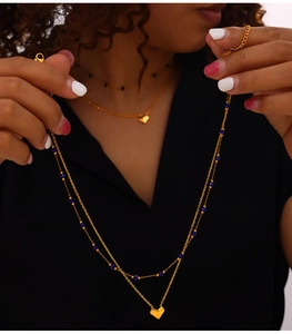 Detail of layered gold heart necklace with blue beads shown on a model neck