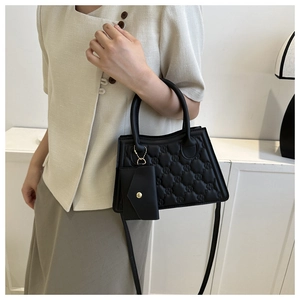 Detail view of black quilted handbag with letter embossing and detachable small pouch