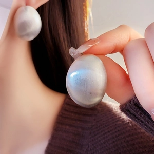 Gros plan de boucles d'oreilles ovales vintage en métal avec une finition argentée mate