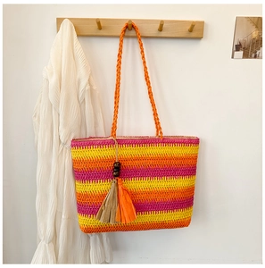 Detail of rainbow stripe straw bag with beaded tassel hanging on a wooden hook