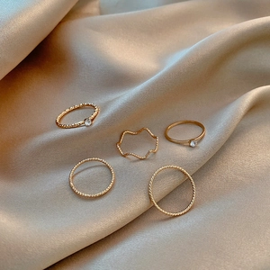 Detailed view of 5-piece gold plated ring set with zircons on champagne silk fabric