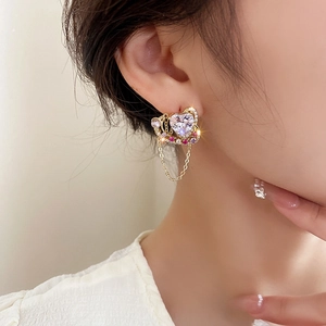 Boucles d'oreilles cœur dorées avec cristaux de zircon et chaînes à franges sur modèle