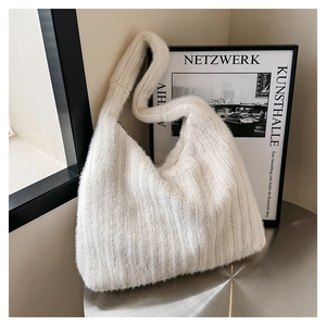 Detailed texture of a white fluffy faux fur tote bag on a modern silver metal table