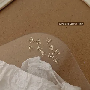 Detailed view of 20 miniature gold ribbon bow nail charms on a refined display